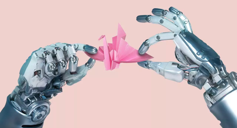 Robot hands folding a pink origami paper crane.