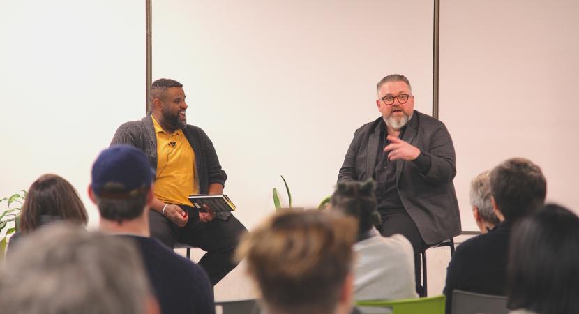 Photograph of Alex Sarian and Elamin Abdelmahmoud talking to a room of people