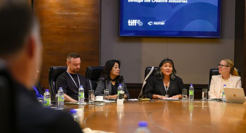 Photograph of people sitting at a large table for a meeting, including Ana Serrano and Anita Lee.